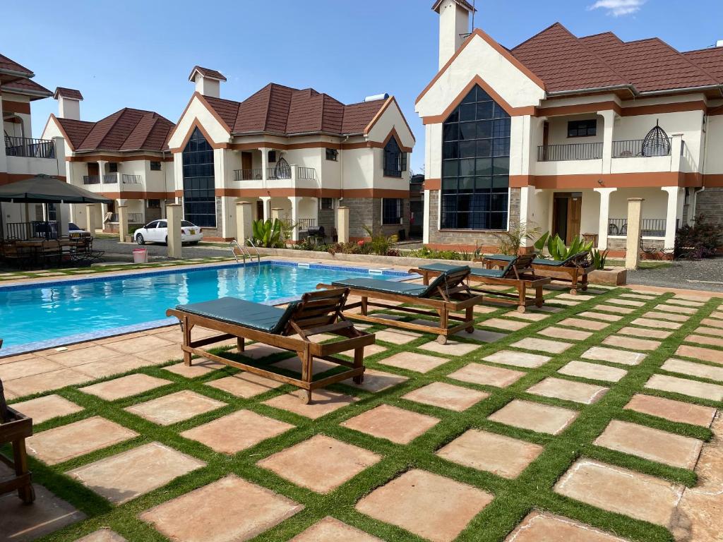 a villa with a swimming pool with benches in front of it at Lifestyle Villas, Nanyuki in Nanyuki