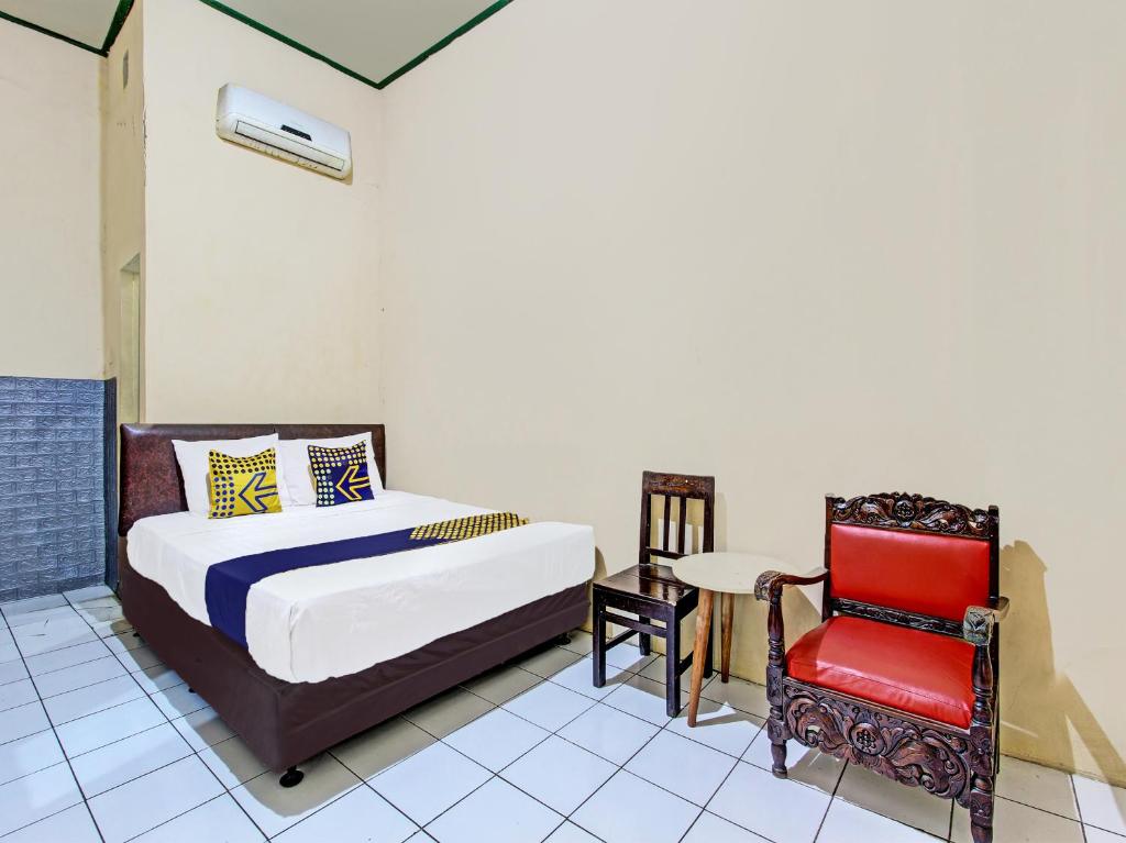 een slaapkamer met een bed en een rode stoel bij SPOT ON 92009 Hotel Indah Arum 