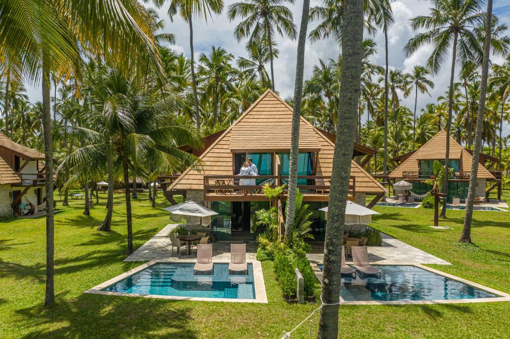 uma villa com um resort com piscina e palmeiras em Pontal dos Carneiros Beach Bungalows em Praia dos Carneiros