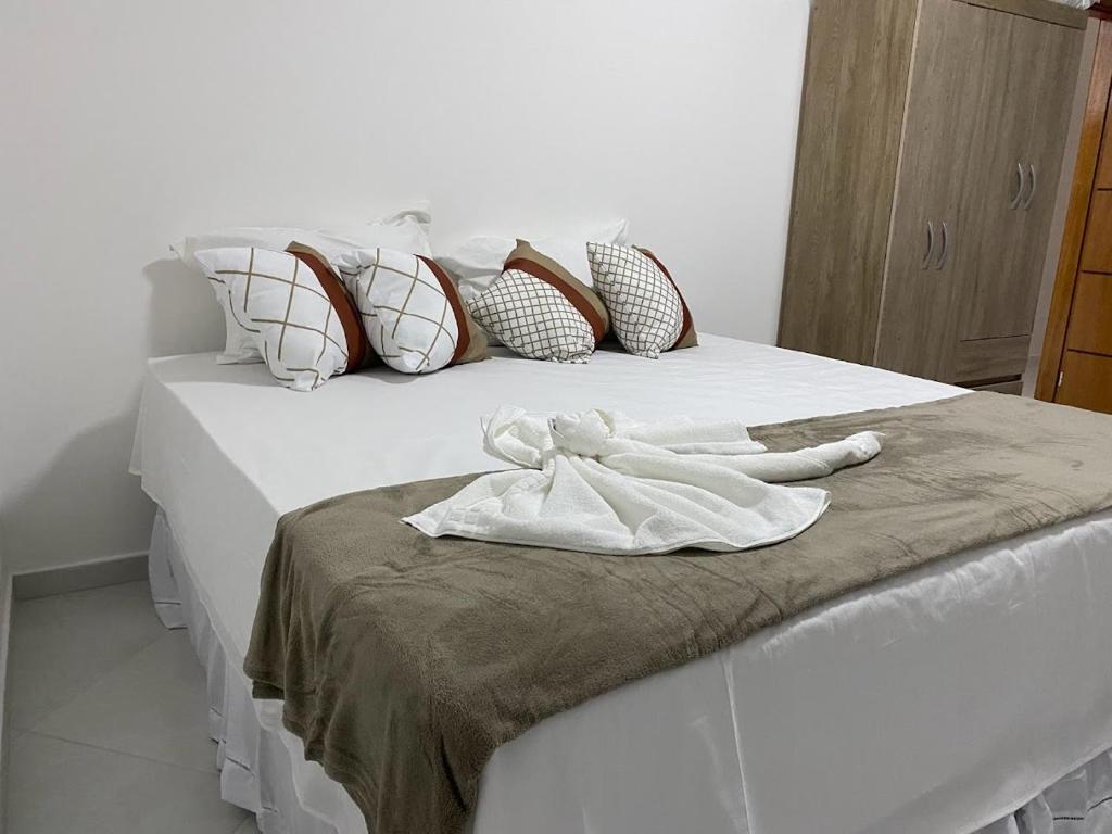 a white robe sitting on top of a bed at POUSADINHA LITORAL in Mucuri
