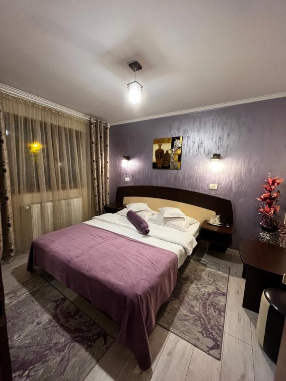 a bedroom with a large bed and a purple wall at Vila Denis in Sinaia