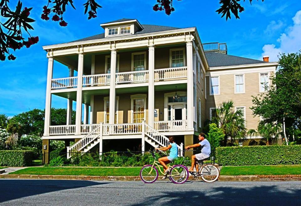 Un uomo e una donna in bicicletta davanti a una casa di The Lasker Inn a Galveston