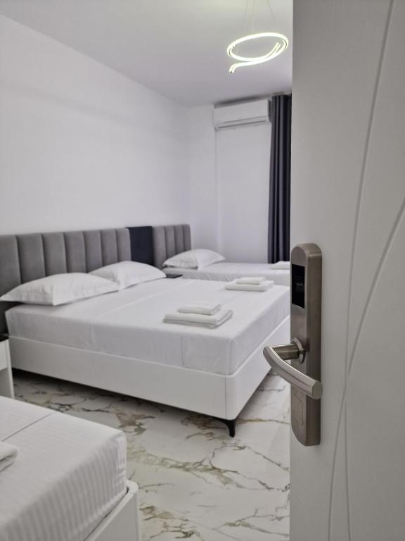 a white room with two beds and a refrigerator at Vila Klari in Ksamil