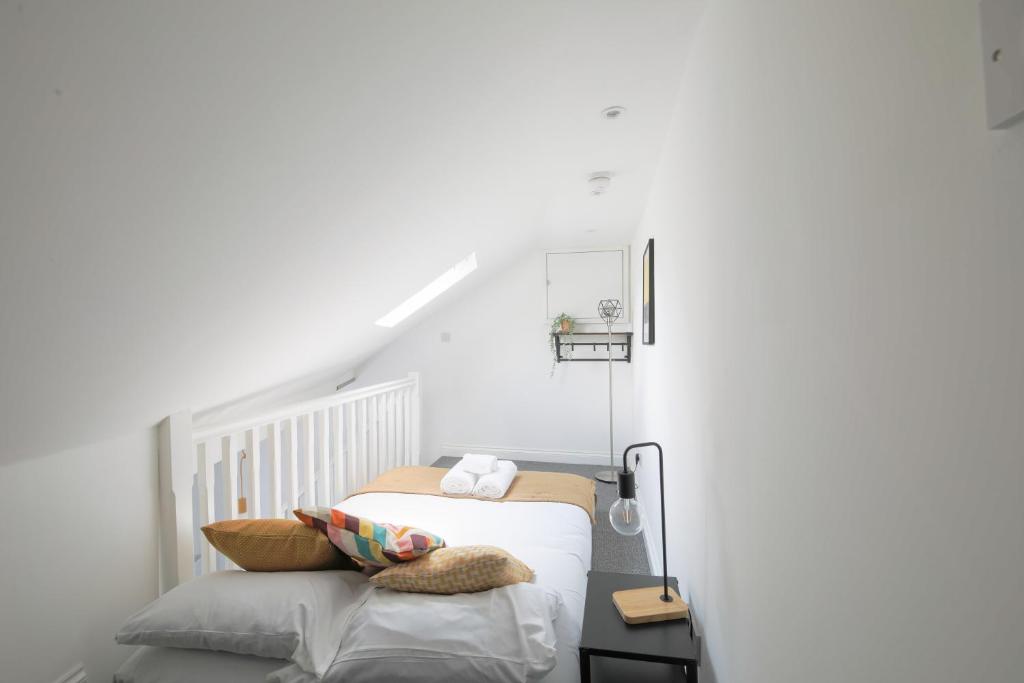 een witte slaapkamer met een bed en een trap bij StayRight Cosy Mezzanine Flat in Vibrant Area - Walking Distance to Central Cardiff in Cardiff