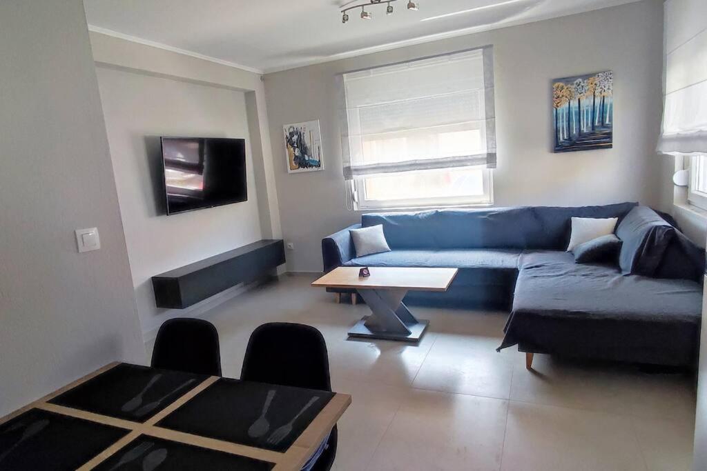 a living room with a blue couch and a table at A & F Apartments - Ari's house in Kalivia Poligirou