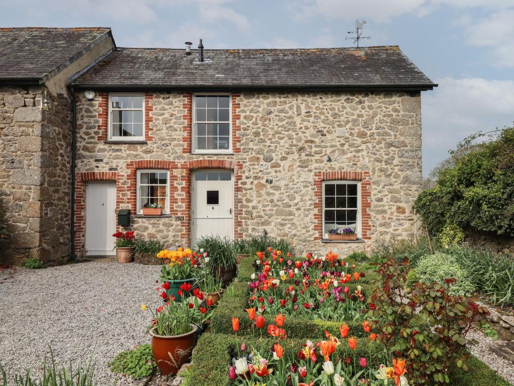 a stone house with flowers in front of it at Monks Cottage in Newton Abbot