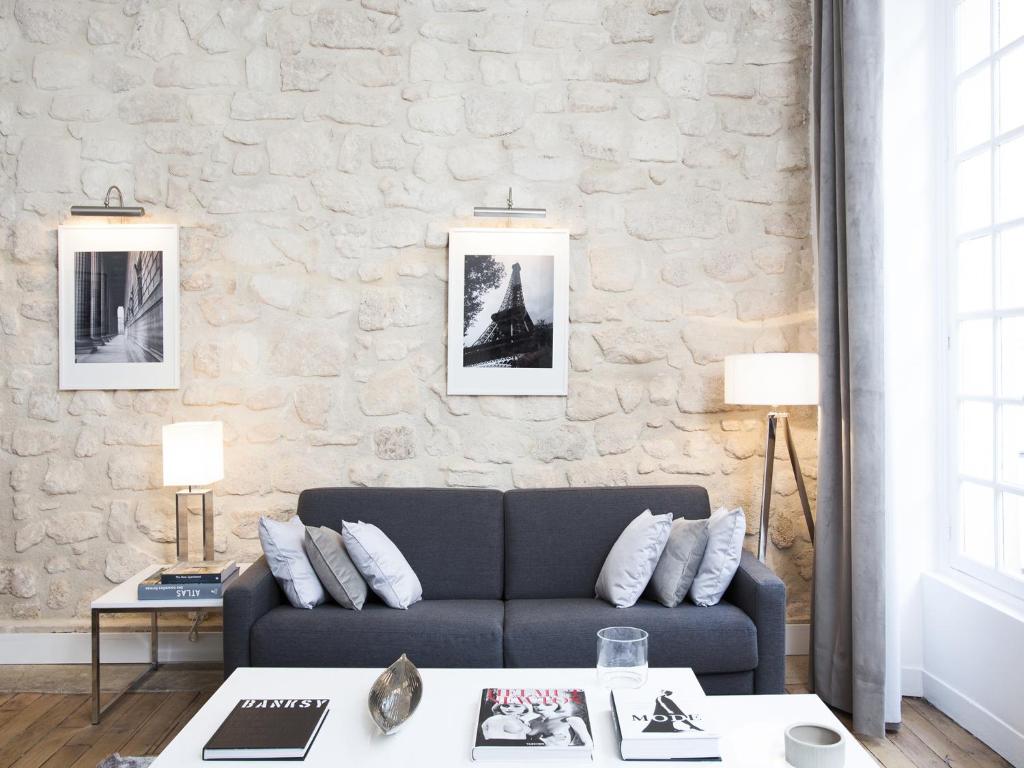 ein Wohnzimmer mit einer Couch und einer Steinwand in der Unterkunft LivinParis - Luxury 2 Bedrooms Le Marais I in Paris