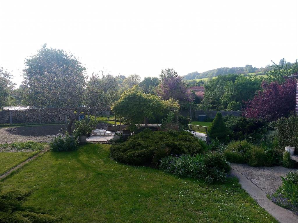 un jardín con césped verde, arbustos y árboles en Chez Nanou en Bailleul-sur-Thérain