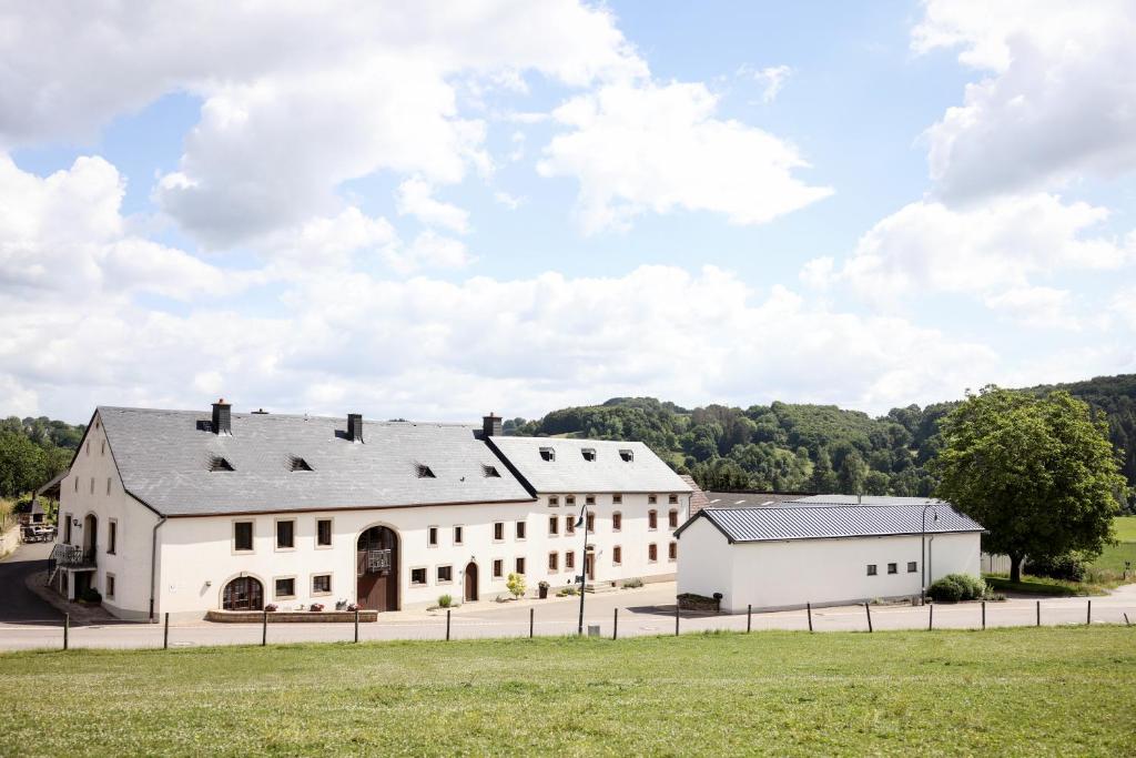 ein großes weißes Gebäude mit einem Grasfeld in der Unterkunft A Mëchels in Bettel