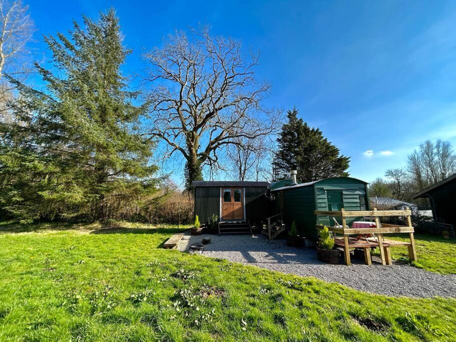 un camping verde con una mesa y un banco en Shepherds Hut in enclosed field en Cardiff