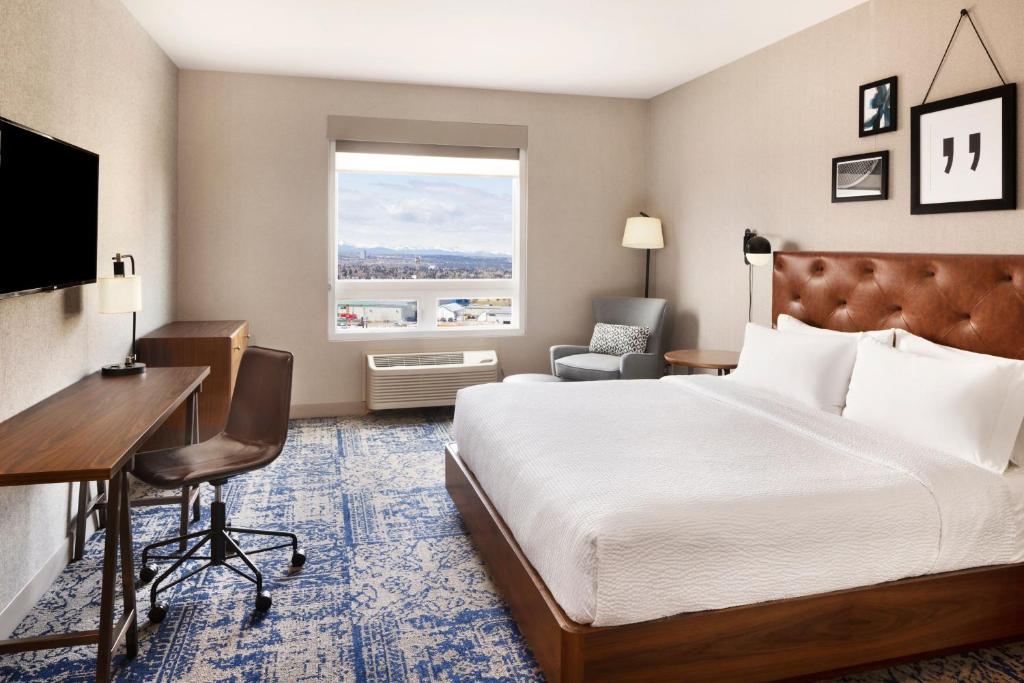 a hotel room with a bed and a desk and a window at Four Points by Sheraton Calgary Airport in Calgary