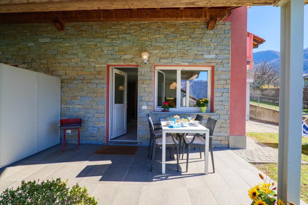 eine Terrasse mit einem Tisch und Stühlen vor einem Backsteingebäude in der Unterkunft Residence Girasole Casa Rossa B in Colico