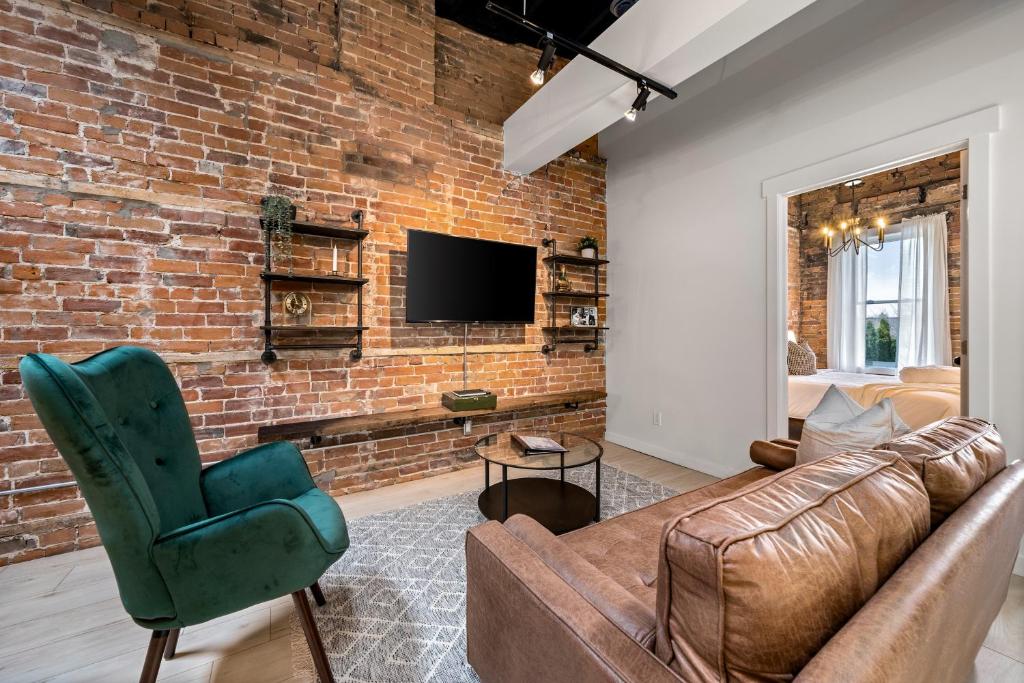 a living room with a couch and a brick wall at The Goodman: Front Street Flats in Belleville