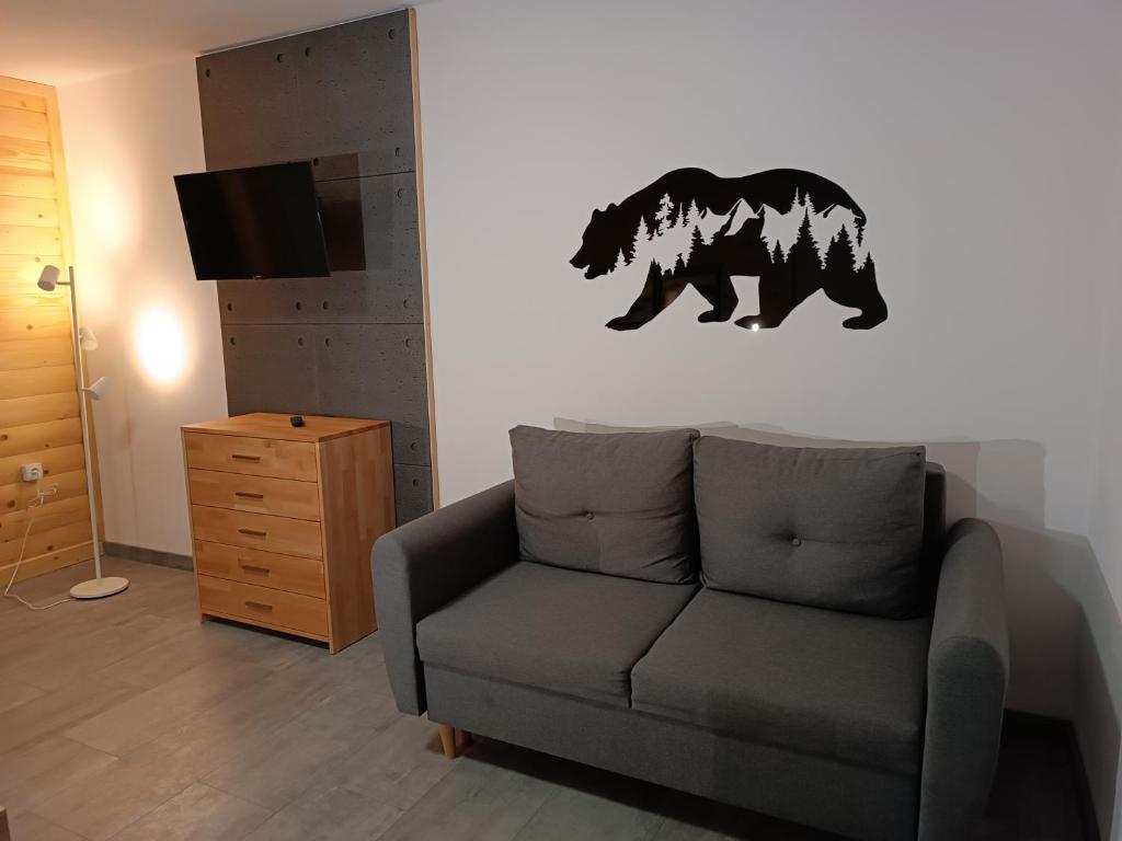a living room with a couch and a bear on the wall at Apartament Bukowy in Zakopane