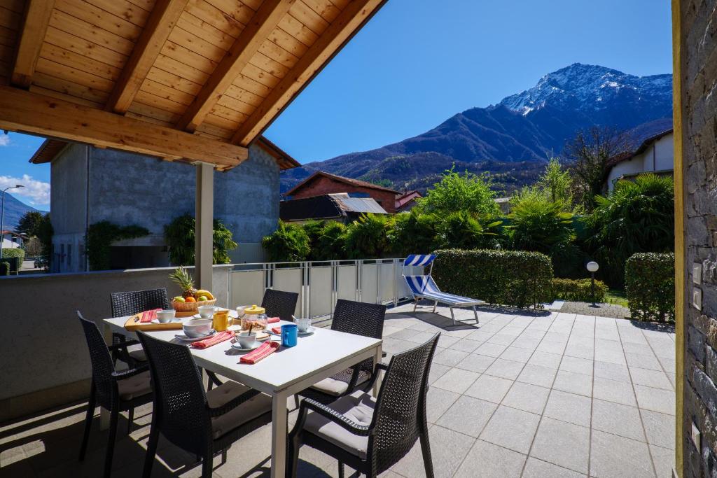 a table and chairs on a patio with mountains in the background at Residence Girasole Casa Gialla in Colico