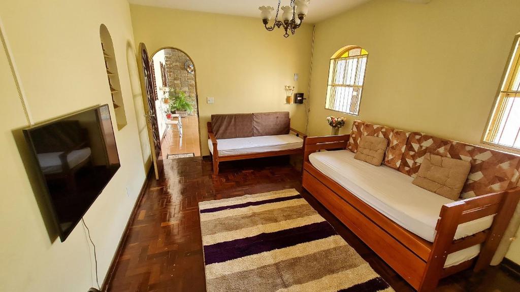 uma sala de estar com um sofá e uma televisão em Casa espaçosa e confortável na região da Pampulha em Belo Horizonte