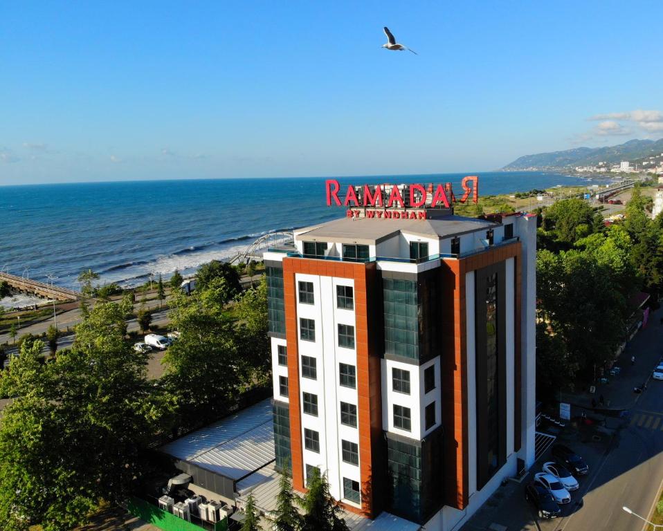 a building with a sign on top of it next to the ocean at Ramada By Wyndham Vakfıkebir in Trabzon