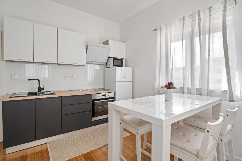 una cocina con armarios blancos y una mesa y sillas blancas. en Apartments Dante, en Podstrana