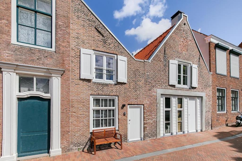 una casa de ladrillo con una puerta azul y un banco en Vakantiehuisje Dichtbij Zee en Vlissingen