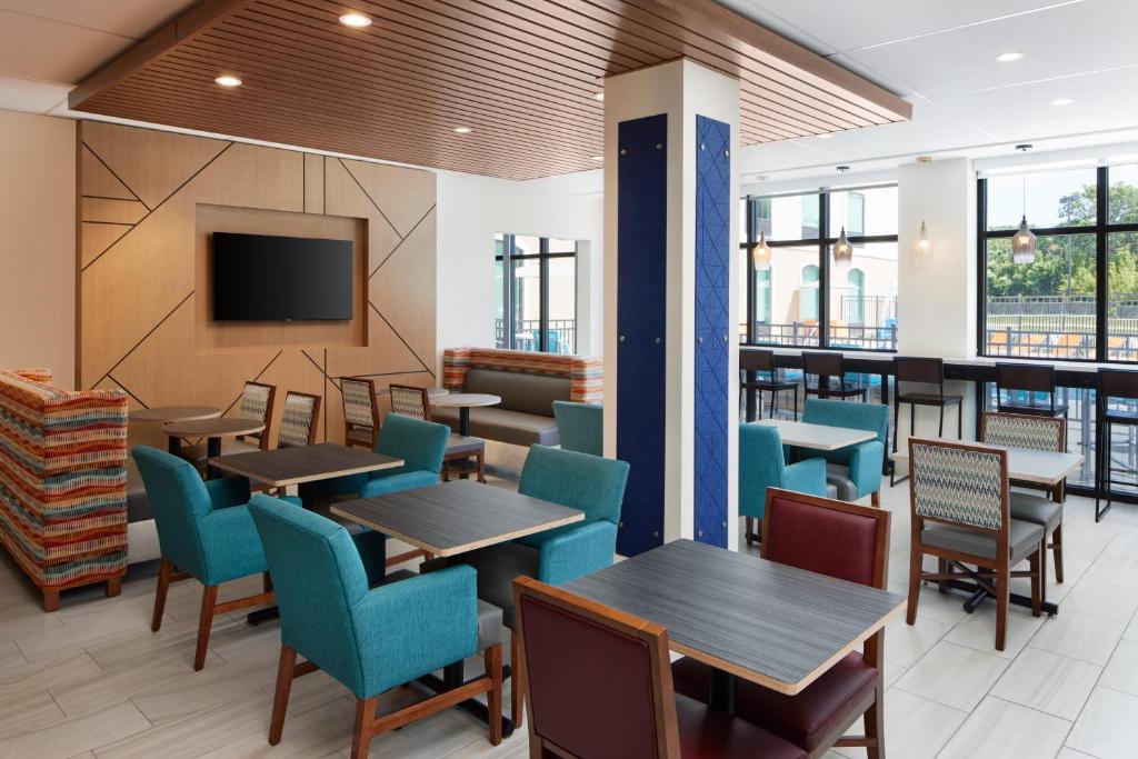 a restaurant with tables and chairs and a flat screen tv at Holiday Inn Express & Suites Gulf Breeze - Pensacola Area by IHG in Gulf Breeze