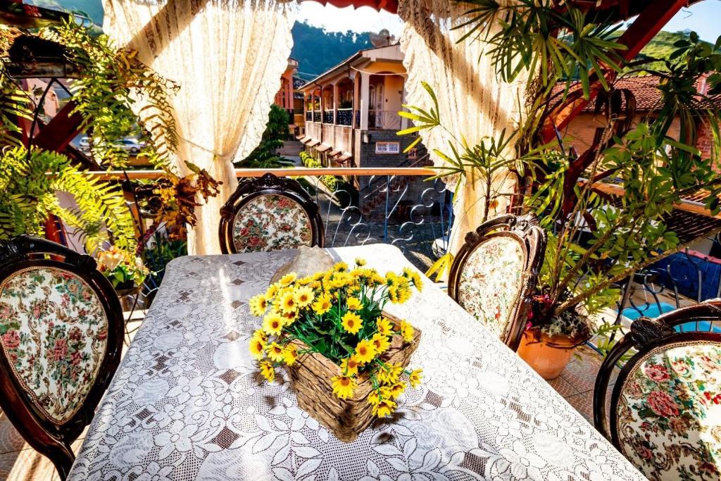 a table with a bouquet of yellow flowers on it at Pousada Oca Porã in Conservatória