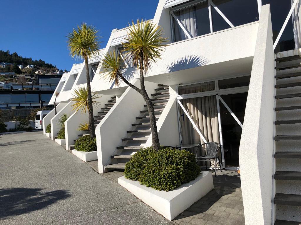 a white building with palm trees in front of it at Amity Serviced Apartments in Queenstown