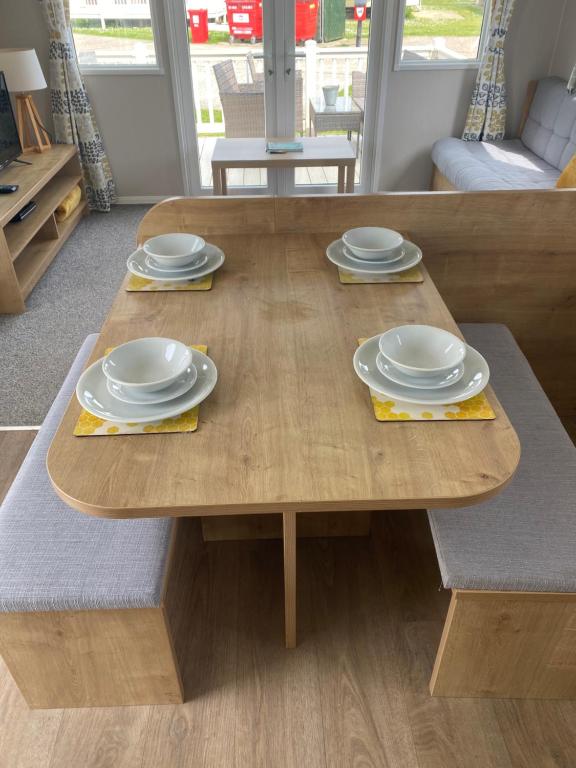 a wooden table with plates and dishes on it at Cosy holiday home at Romney Sands in New Romney
