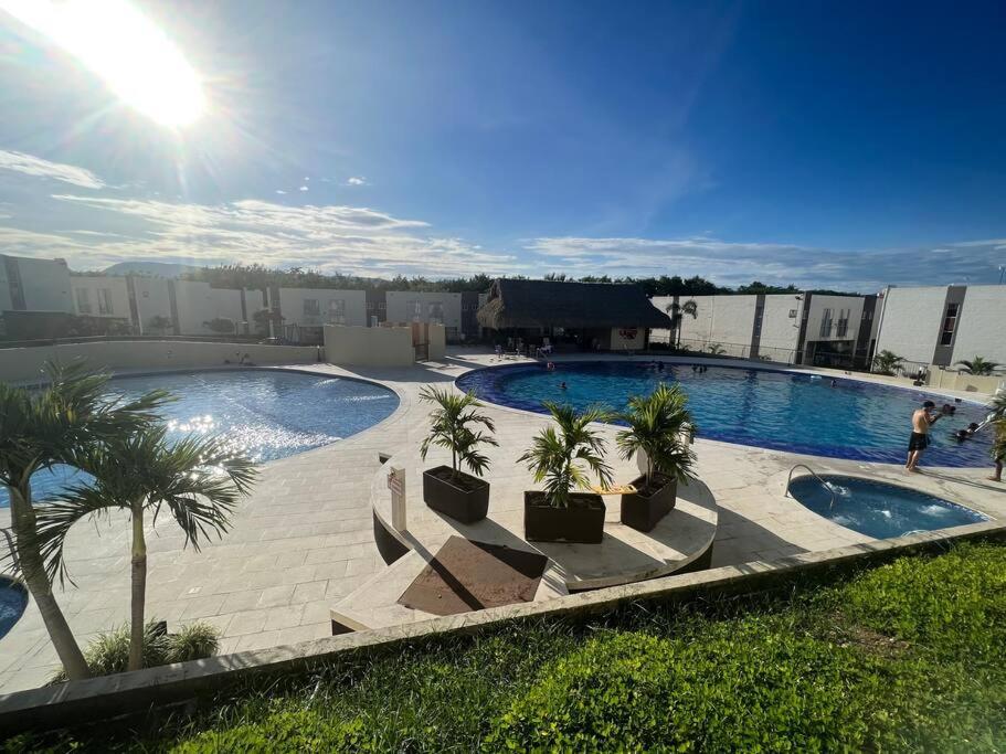 - une grande piscine bordée de palmiers à côté d'un bâtiment dans l'établissement Hermosa casa muy equipada para descansar, à Ricaurte