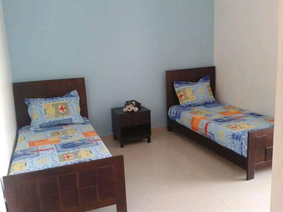 um quarto com duas camas e uma mesa de cabeceira em Le 21 Armada Tower em Bouznika