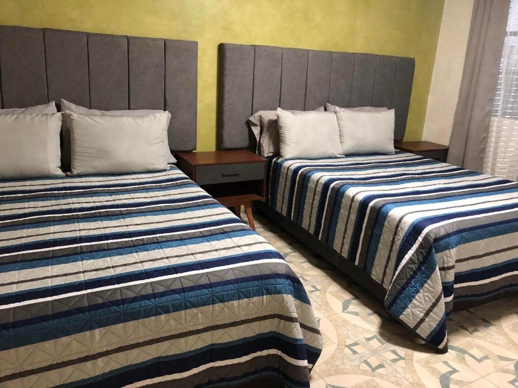 dos camas sentadas una al lado de la otra en una habitación en Suites Incoreli 4, Centro Pachuca de Soto en Pachuca de Soto