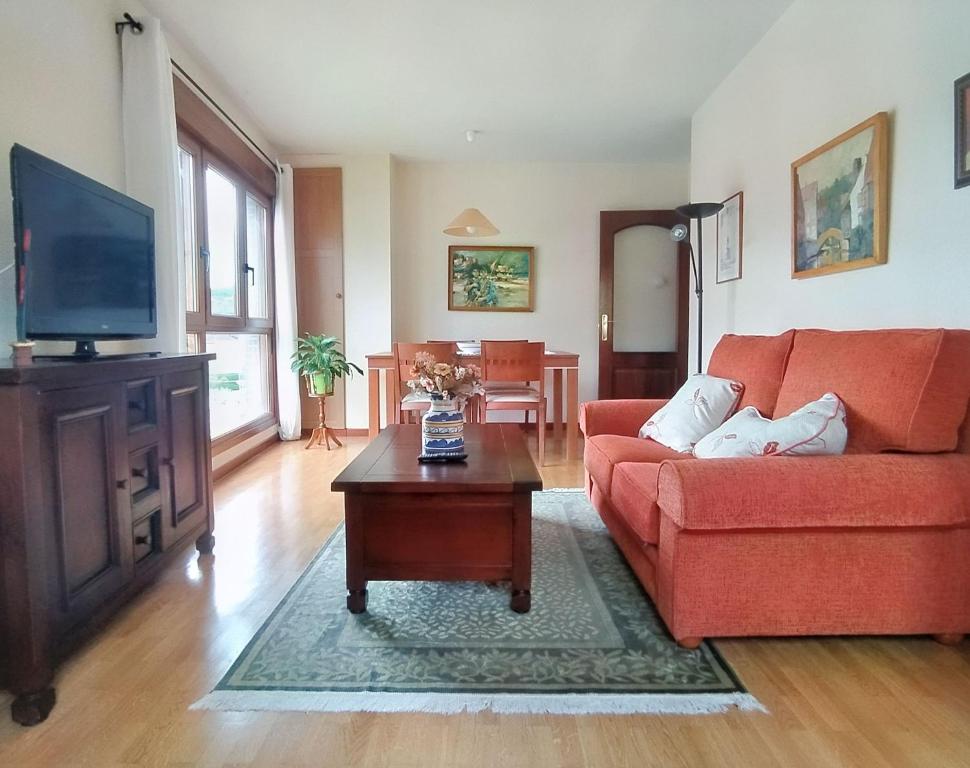 sala de estar con sofá rojo y TV en Apartamento Seronda, en Villaviciosa