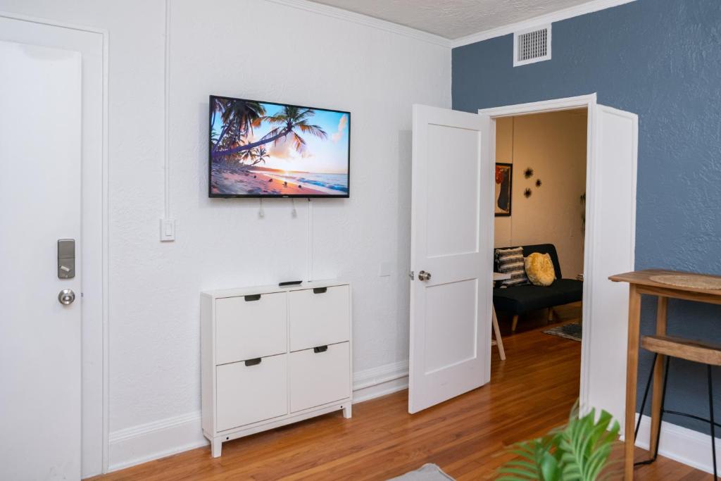 een woonkamer met een witte kast en een tv aan de muur bij Comfy Little Havana Apt - Centrally located Hv2 in Miami