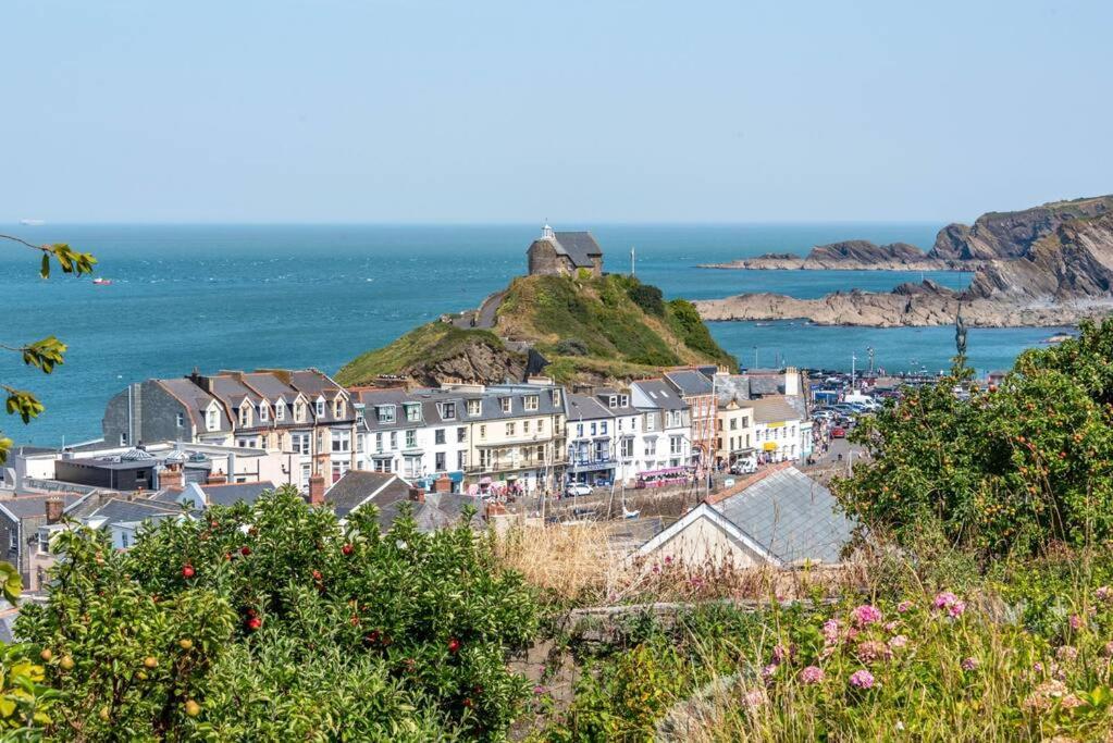 a group of buildings on a hill next to the ocean at The Tempest, sea views, coastal & rural walks. in Ilfracombe