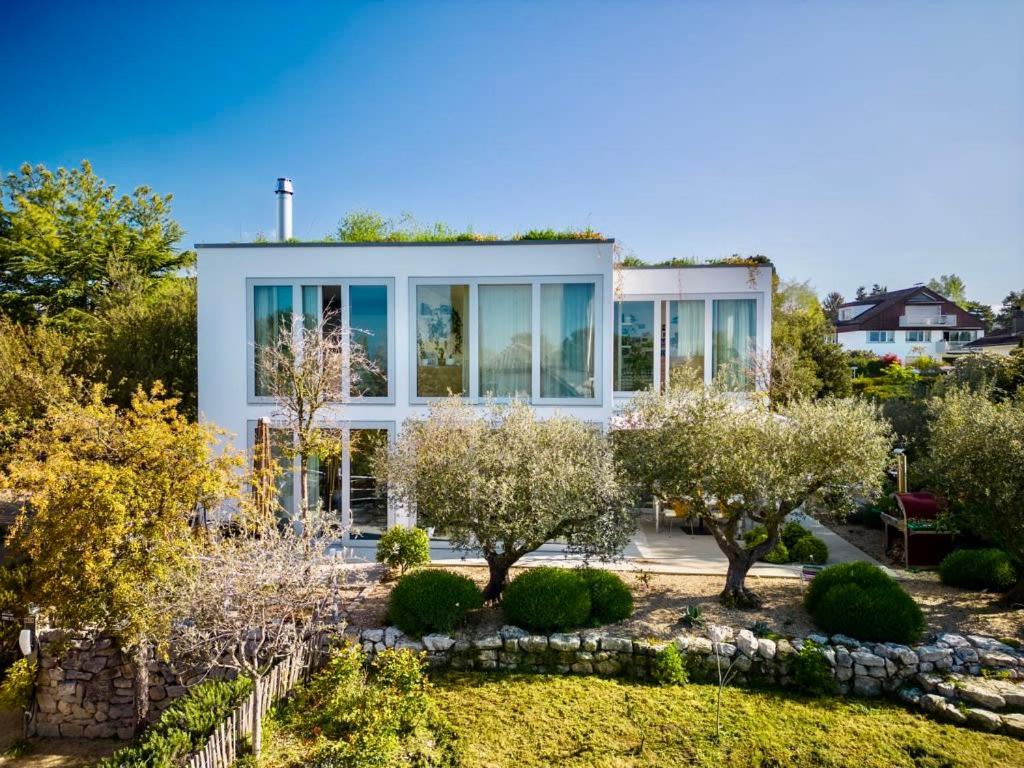uma casa com um jardim em frente em Villa Serenity Sustainable Luxury Retreat by GuestLee em Preverenges