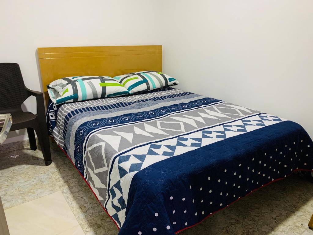 a bed with a blue and white comforter and pillows at Bogotá Kings 302 in Bogotá