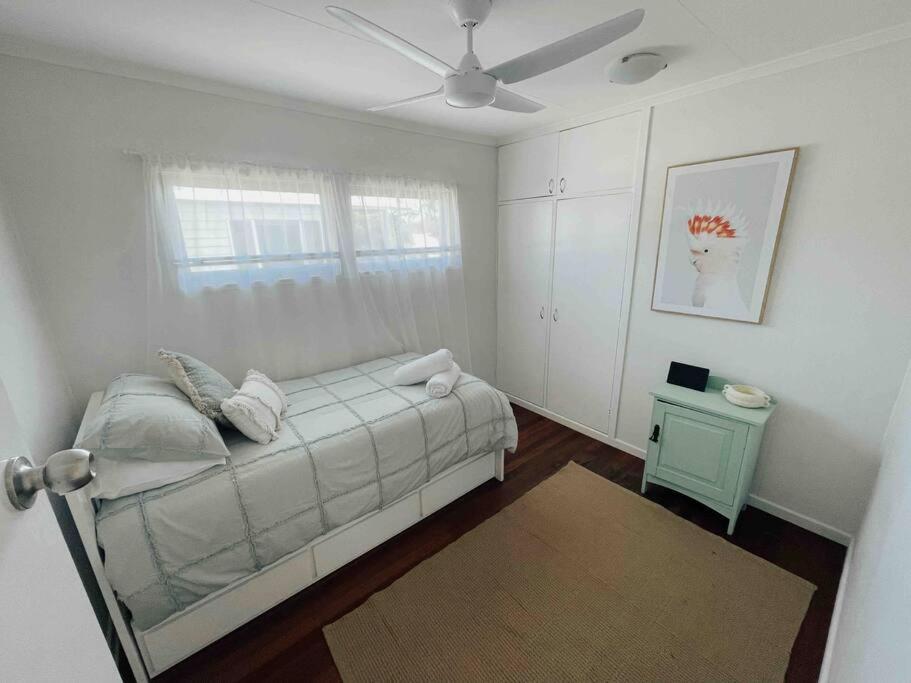 a white bedroom with a bed and a window at Beach House @ Moffat in Caloundra