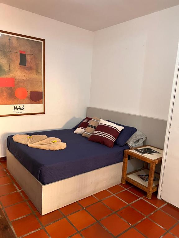 Un dormitorio con una cama con sábanas azules y una mesa. en Un rinconcito en Pampatar en Pampatar