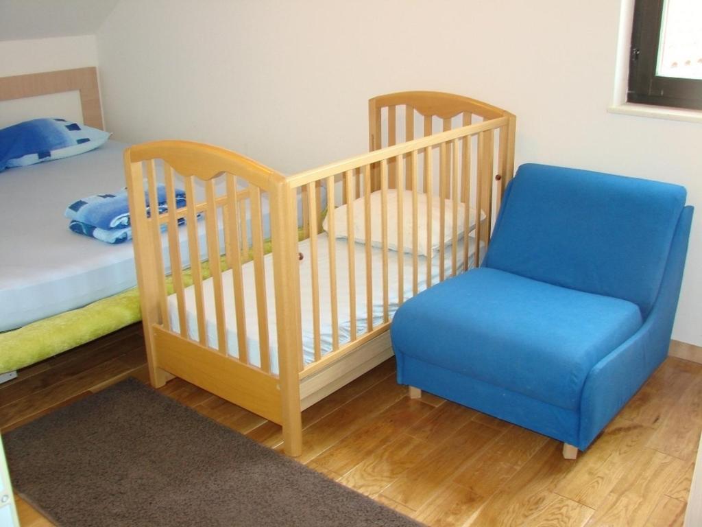 a crib with a blue chair and a bed at Apartments by the sea Kaprije - 20012 in Kaprije