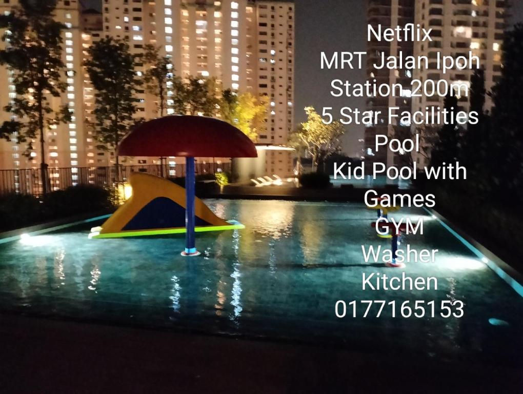 a playground with an umbrella in the water at night at The Pano Jalan Ipoh Sentul by Kenangan Homes in Kuala Lumpur