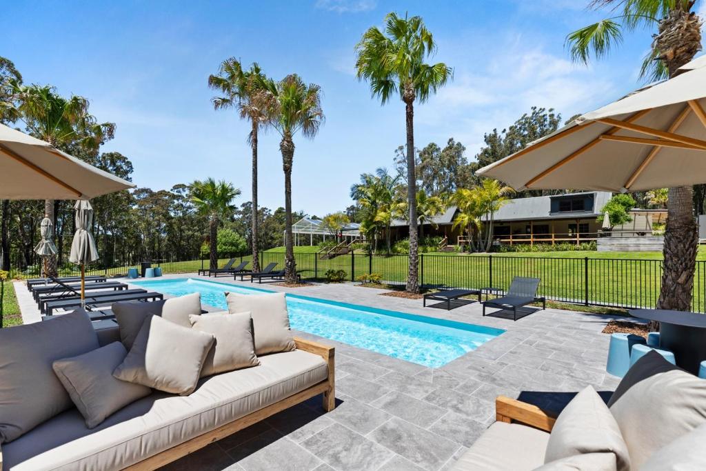 a villa with a swimming pool with a couch and umbrellas at Jackson Ranch by Bannisters in Bawley Point