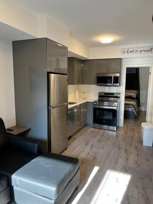 een keuken met roestvrijstalen apparatuur en een woonkamer bij Lovely one bedroom condo with free parking in Niagara Falls