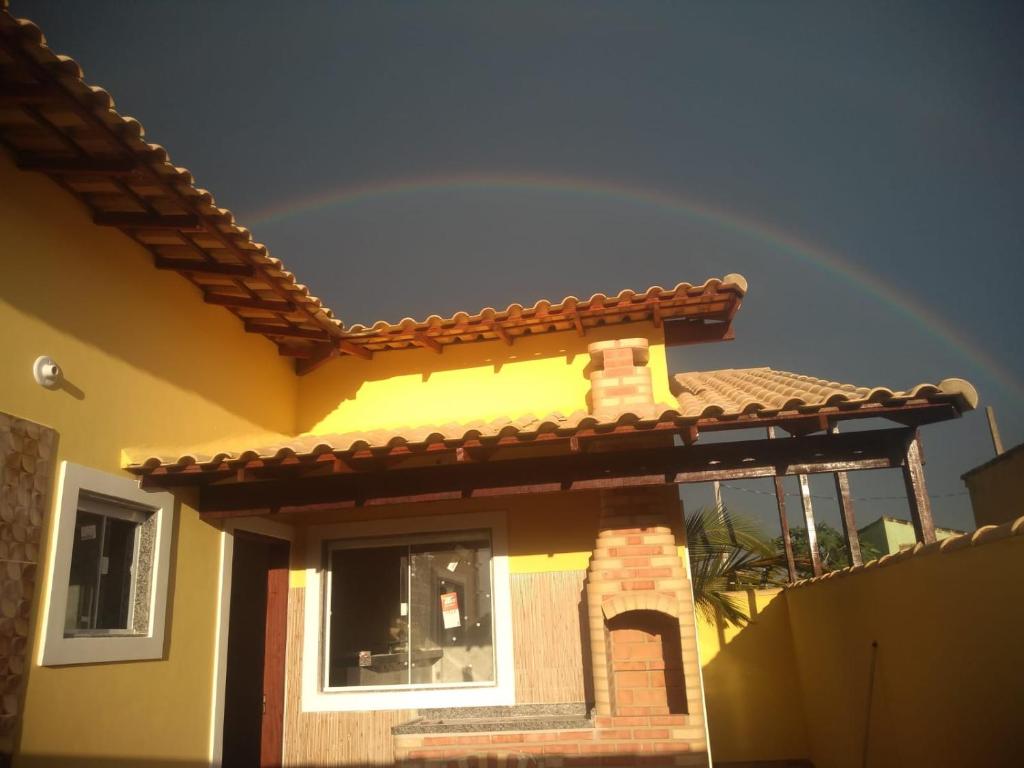 a rainbow in the sky above a house at Casa amarela 1 quarto in Cabo Frio