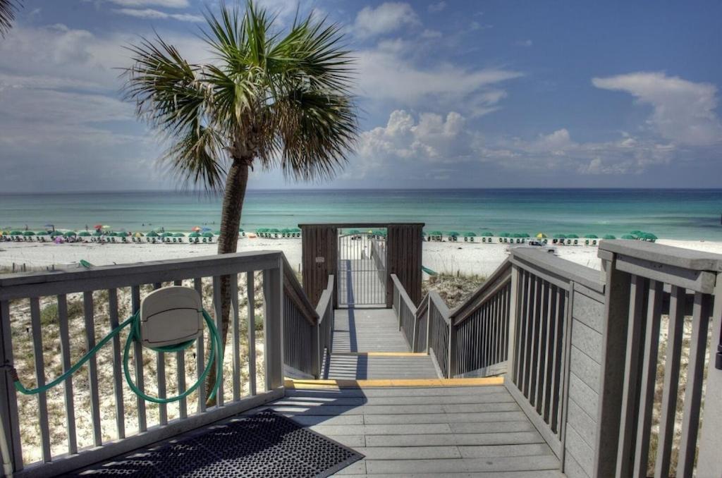 una escalera a la playa con una palmera en Gated Gulf Front Condo in Hidden Dunes Beach & Tennis Resort, en Destin