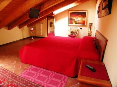 a bedroom with a large red bed in a room at Corte Nuova in Valeggio sul Mincio