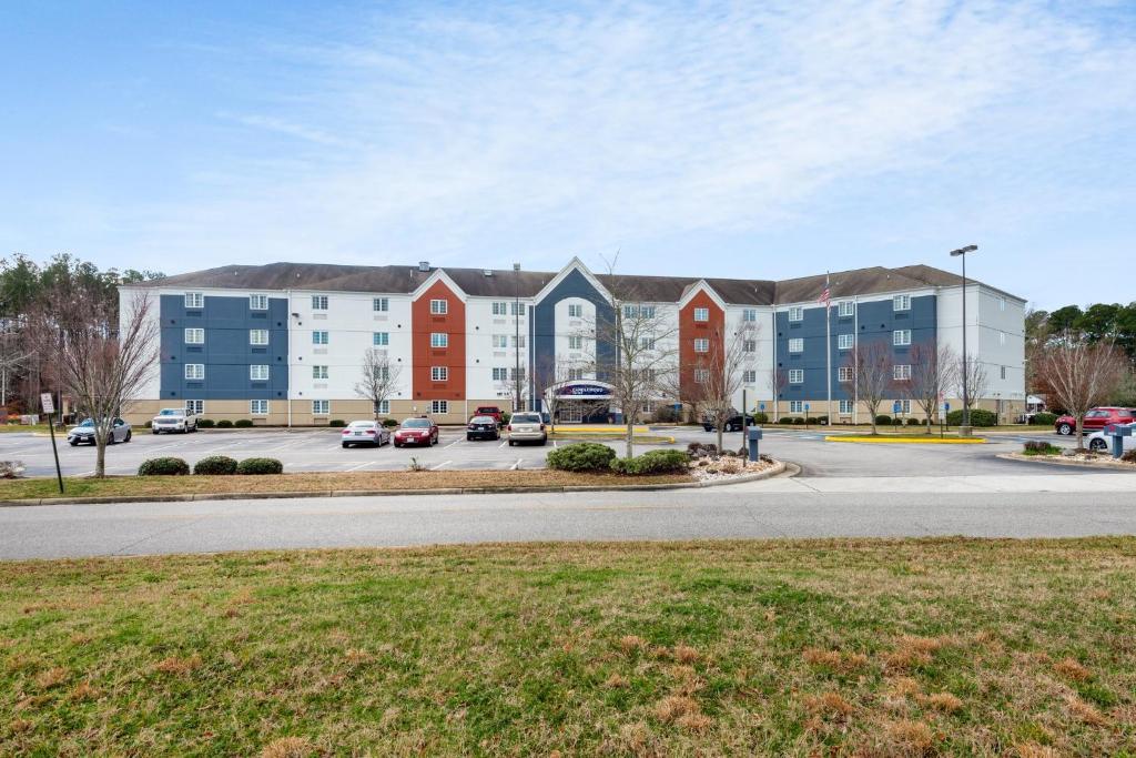 un edificio con coches estacionados en un estacionamiento en Candlewood Suites Chesapeake-Suffolk, an IHG Hotel, en Chesapeake