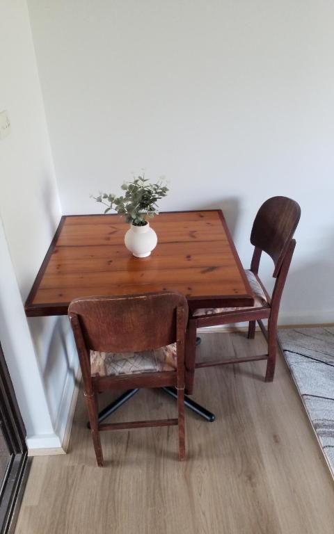 a wooden table with two chairs and a vase on it at Tranquil Studio Apartment Just 3km from Port Pirie in Port Pirie