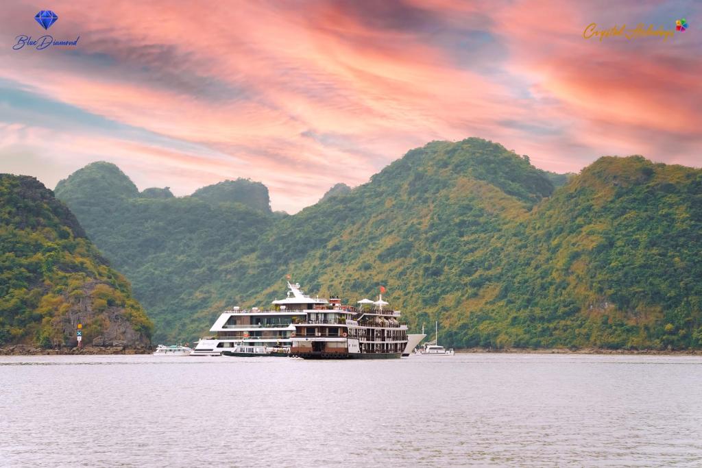 a cruise ship on the water with mountains in the background at Blue Diamond Cruise in Ha Long