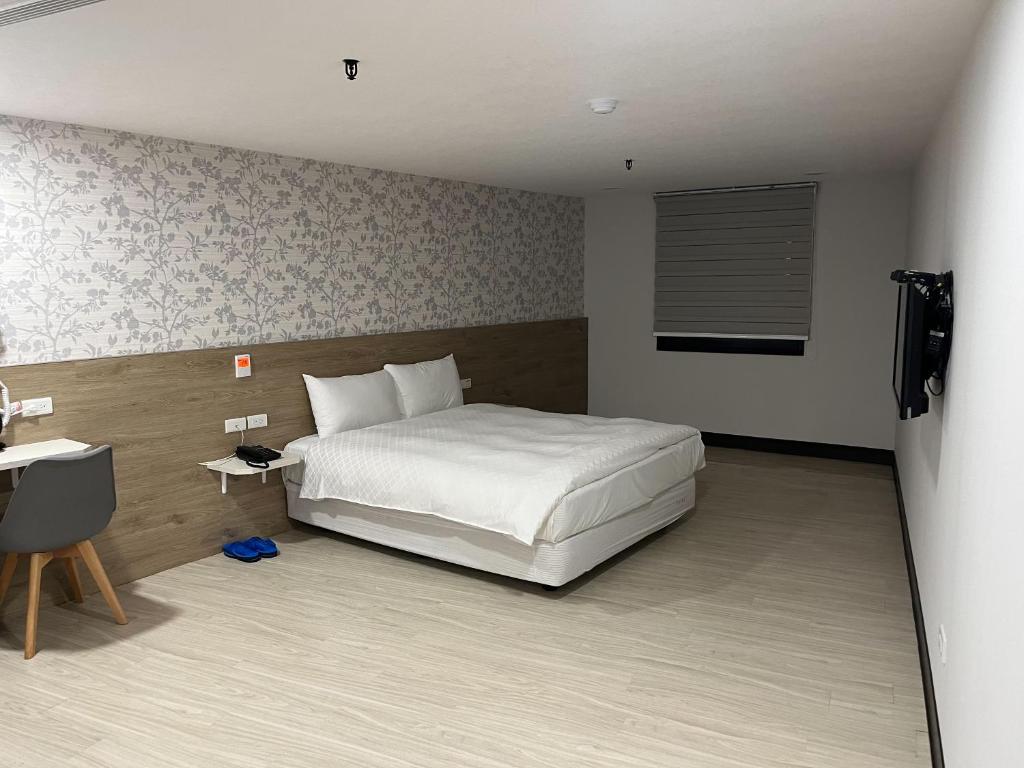 a bedroom with a white bed and a television at Tie Dao Hotel in Tainan