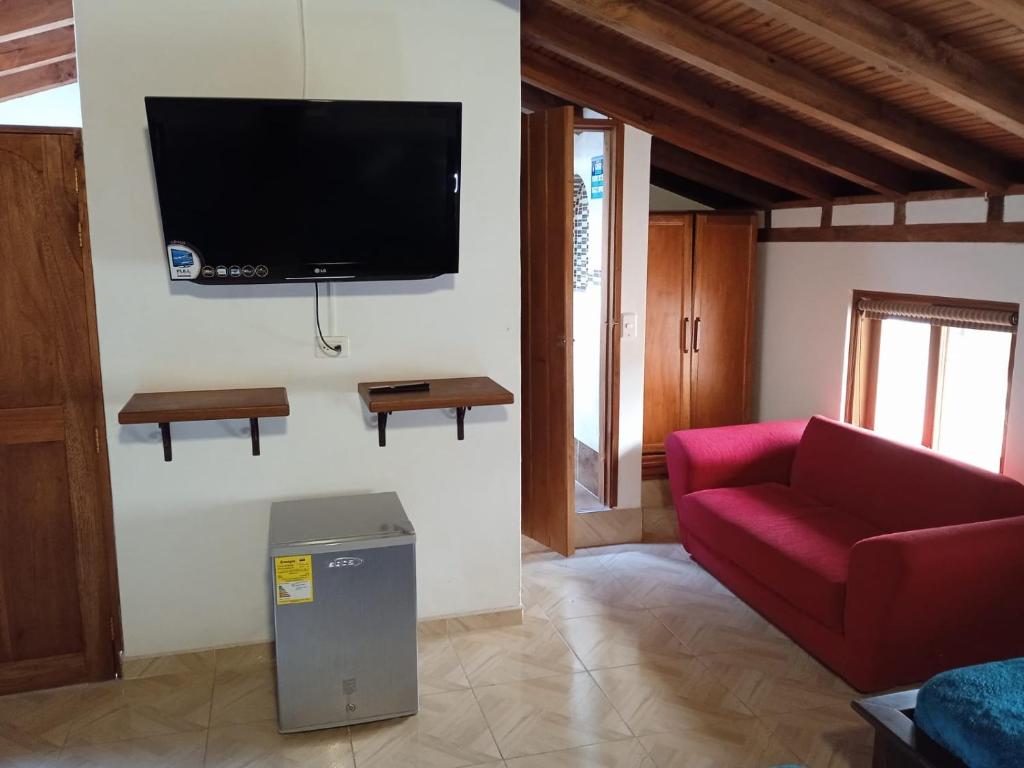 ein Wohnzimmer mit einem roten Sofa und einem Flachbild-TV in der Unterkunft Hospedaje Casa Versalles in Villa de Leyva
