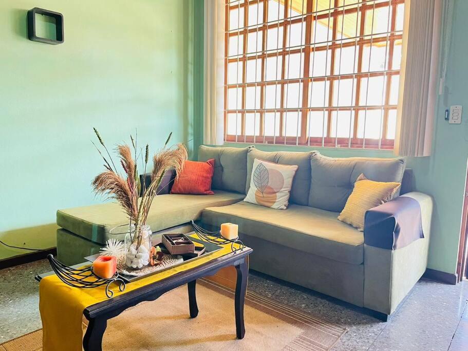 阿拉胡埃拉的住宿－Alojamiento Tiquicia Valley，客厅配有沙发和桌子